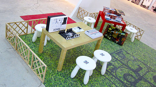 Photograph of the Board Games section of Random Blends 2011, surrounded by fences and distinguished with a large grass patch on the floor.