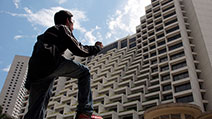 Photograph of a photographer climbing a tall but seemingly short building, through the application of forced perspective.