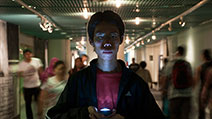 Photograph of a photographer creating a dramatic and mysterious mood with light cast from a low angle, and motion blur of people moving in the background.