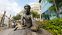 Photograph of the statue of an Indian coolie loading goods onto a bullock cart, which is part of a bronze sculpture series, The River Merchants by Aw Tee Hong, at Boat Quay, Singapore.